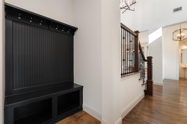 mudroom with a high ceiling, an inviting chandelier, dark wood-type flooring, visible vents, and baseboards