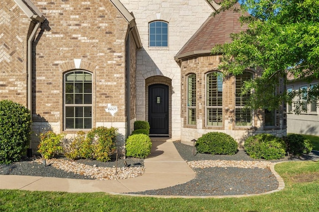 view of exterior entry with brick siding and stone siding
