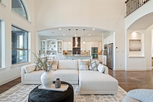 living area featuring baseboards, wood finished floors, and a high ceiling