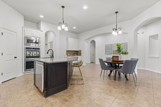 2632 Los Alamos Pass, Round Rock, TX 78665 - kitchen featuring appliances with stainless steel finishes, a sink, light stone counters, a chandelier, and an island with sink
