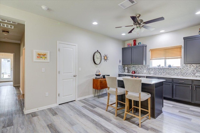 10312 Bankhead Dr, Austin, TX 78747 - kitchen featuring a sink, backsplash, a kitchen bar, a center island, and light wood-style floors