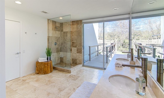 9707 Timber Ridge Pass, Austin, TX 78733 - bathroom featuring tiled shower, double vanity, a wall of windows, and recessed lighting