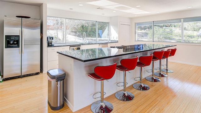 9707 Timber Ridge Pass, Austin, TX 78733 - kitchen with appliances with stainless steel finishes, white cabinets, healthy amount of natural light, a kitchen bar, and recessed lighting