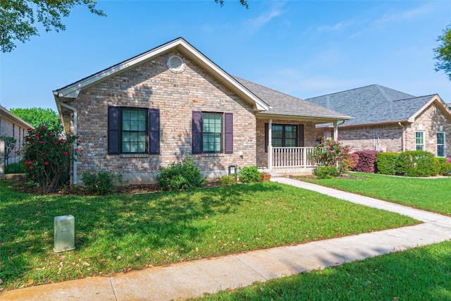 single story home featuring covered porch, a front lawn, and brick siding