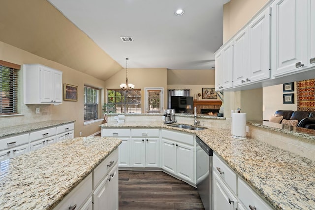 kitchen with a sink, white cabinetry, vaulted ceiling, stainless steel dishwasher, and decorative backsplash