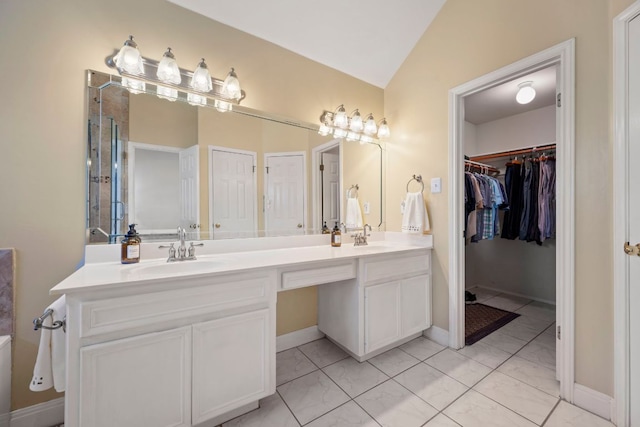 bathroom featuring a sink, a walk in closet, double vanity, and lofted ceiling