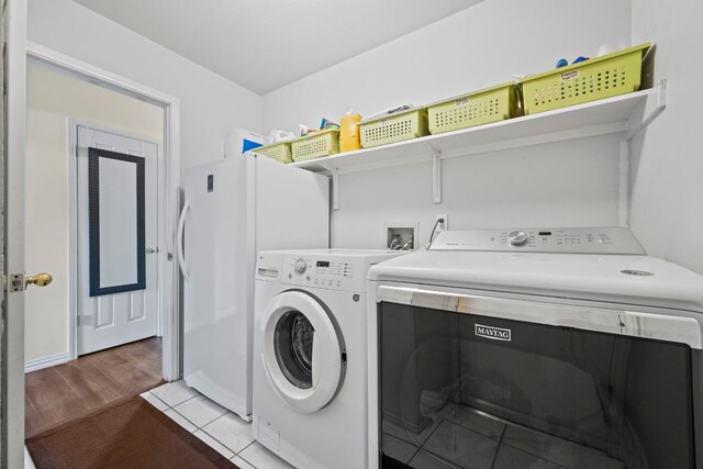 washroom with washer and clothes dryer, laundry area, and wood finished floors