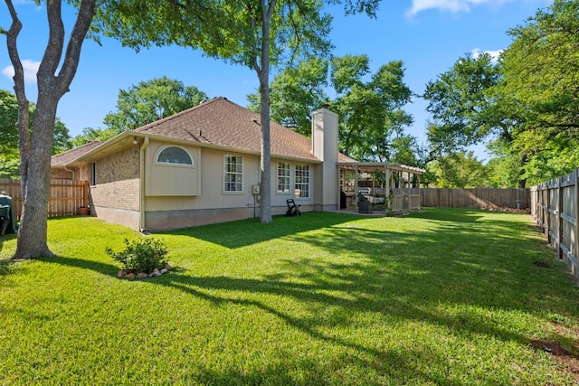 rear view of property with a yard, a fenced backyard, roof with shingles, brick siding, and a chimney
