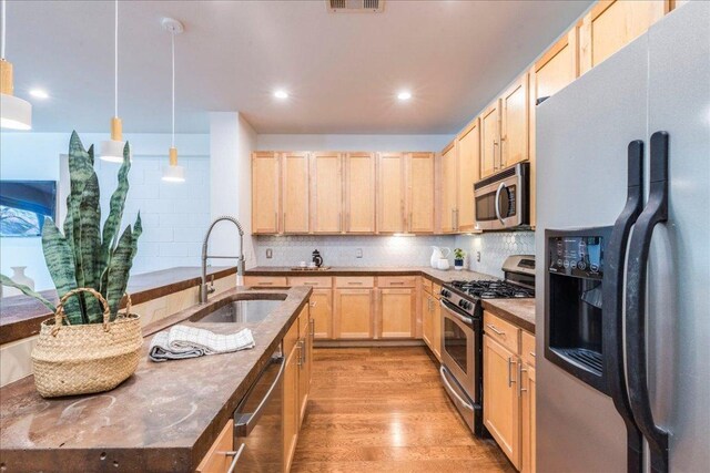 2608 E 6th St Unit 6, Austin, TX 78702 - kitchen with stainless steel appliances, light brown cabinets, a sink, decorative backsplash, and light wood-style flooring