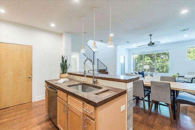 2608 E 6th St Unit 6, Austin, TX 78702 - kitchen with stainless steel dishwasher, a sink, dark countertops, open floor plan, and wood finished floors