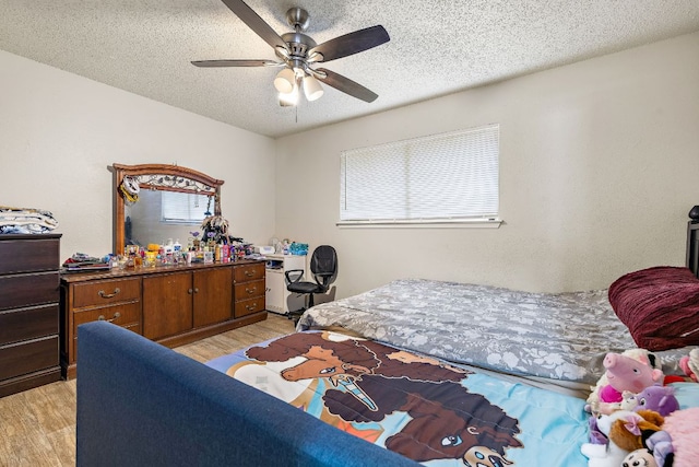bedroom with ceiling fan, light wood finished floors, and a textured ceiling