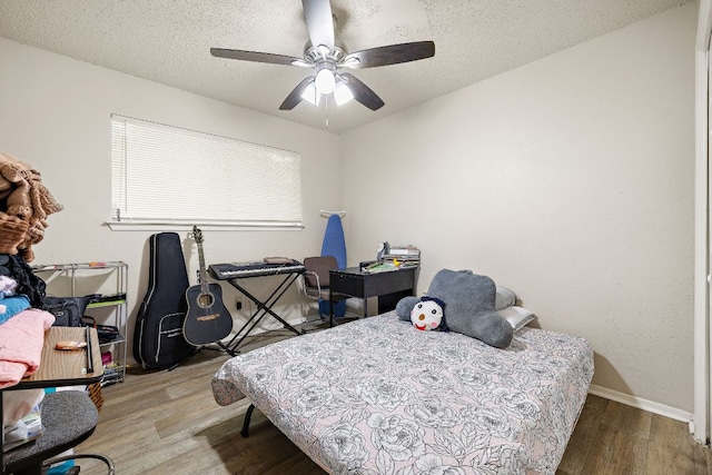 bedroom with baseboards, a ceiling fan, wood finished floors, and a textured ceiling