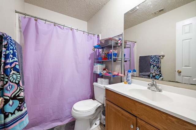 bathroom featuring visible vents, toilet, vanity, and a textured ceiling