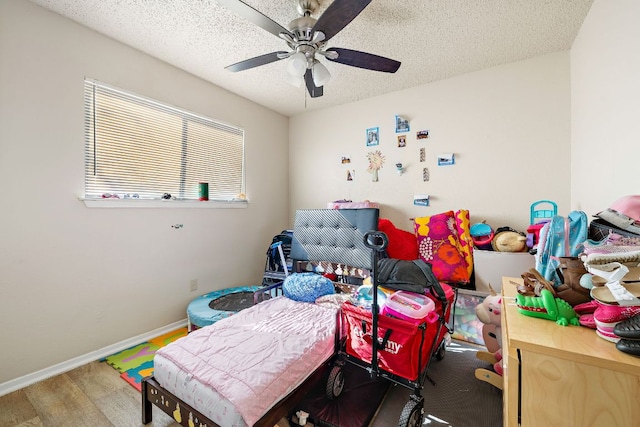recreation room featuring a textured ceiling, wood finished floors, ceiling fan, and baseboards