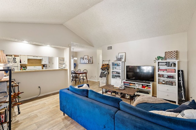 living area featuring light wood finished floors, visible vents, a textured ceiling, and lofted ceiling