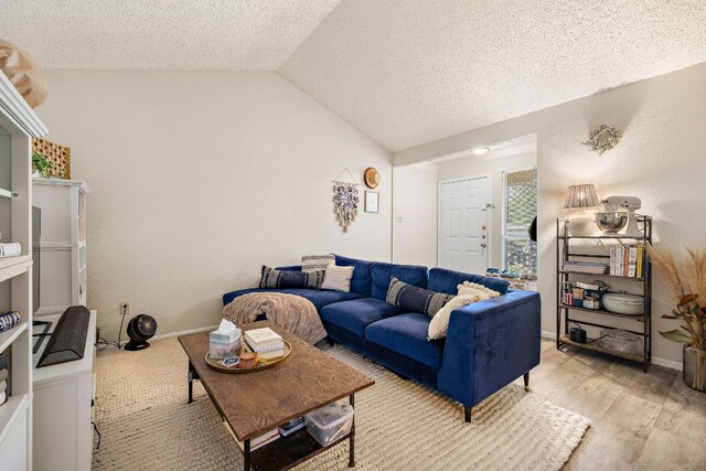 living room with light wood-style flooring, baseboards, vaulted ceiling, and a textured ceiling