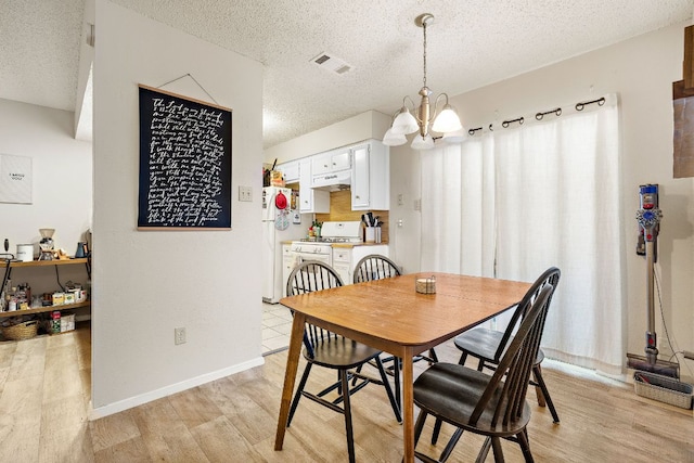 dining area with a notable chandelier, visible vents, a textured ceiling, and light wood-style flooring