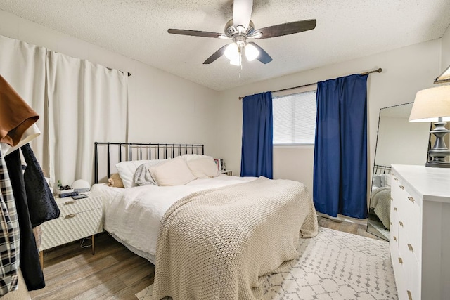 bedroom with a textured ceiling, wood finished floors, and a ceiling fan