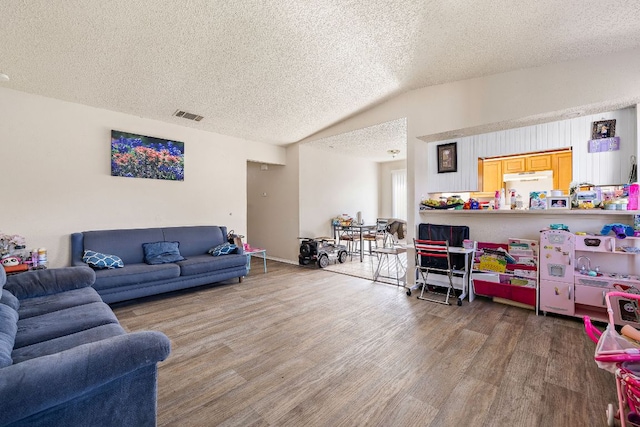 living room featuring a textured ceiling, wood finished floors, lofted ceiling, and visible vents