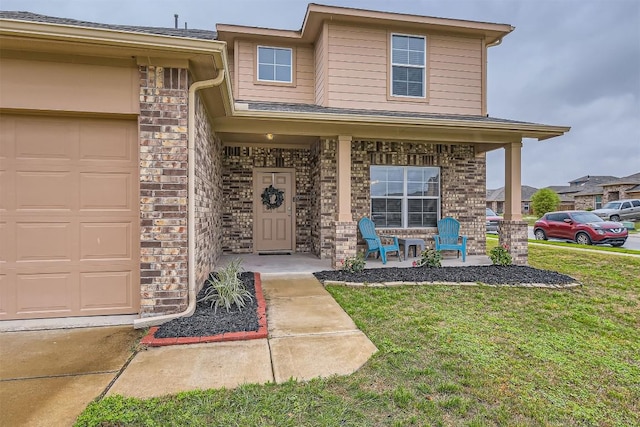 2232 Baugh Rd, Austin, TX 78754 - property entrance featuring covered porch, a yard, a garage, and brick siding