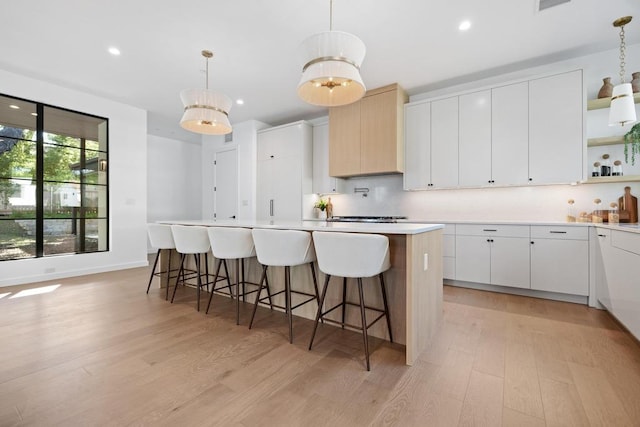 3412 Rosefinch Trl, Austin, TX 78746 - kitchen with open shelves, light wood finished floors, light countertops, an island with sink, and recessed lighting