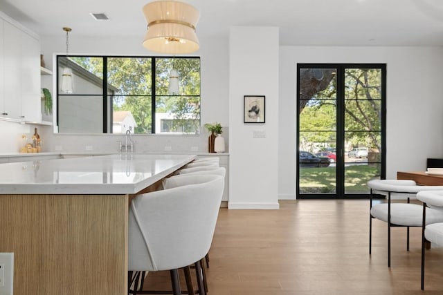 3412 Rosefinch Trl, Austin, TX 78746 - kitchen featuring light wood-style floors, white cabinetry, open shelves, a breakfast bar, and open floor plan