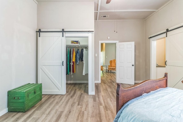 1132 W Clark St, Bartlett, TX 76511 - bedroom with a barn door, light wood-style floors, a walk in closet, a closet, and baseboards