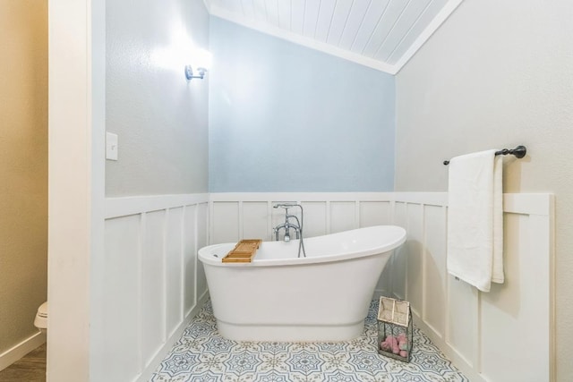 1132 W Clark St, Bartlett, TX 76511 - bathroom with a soaking tub, a wainscoted wall, a decorative wall, toilet, and tile patterned flooring