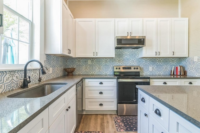1132 W Clark St, Bartlett, TX 76511 - kitchen with appliances with stainless steel finishes, a sink, white cabinetry, light stone counters, and backsplash