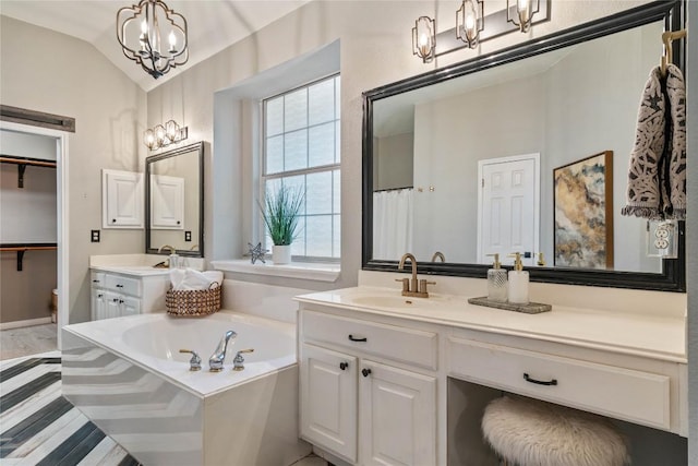 bathroom with a chandelier, a garden tub, vaulted ceiling, vanity, and wood finished floors