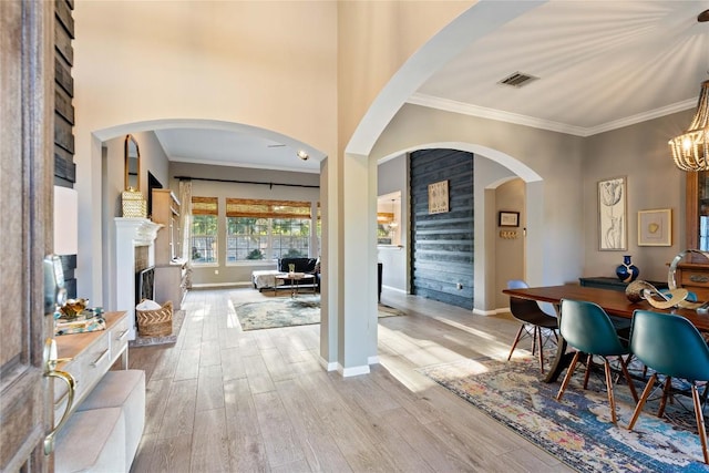 entryway with a fireplace, wood finished floors, ornamental molding, baseboards, and arched walkways