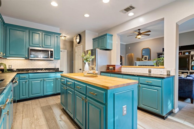 kitchen featuring stainless steel appliances, wooden counters, a kitchen island, a ceiling fan, and light wood finished floors