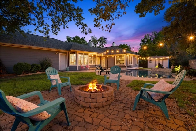 rear view of house with a fire pit, a patio, an outdoor pool, an outdoor structure, and a lawn