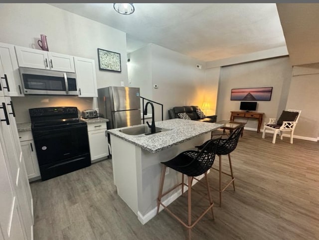 5918 Lago Vista Way Unit D32, Leander, TX 78645 - kitchen featuring appliances with stainless steel finishes, a sink, wood finished floors, white cabinets, and a breakfast bar