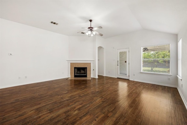 18513 Silent Water Way, Pflugerville, TX 78660 - unfurnished living room featuring dark wood-style flooring, a tile fireplace, a ceiling fan, arched walkways, and vaulted ceiling