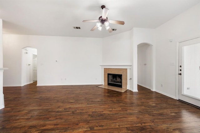 18513 Silent Water Way, Pflugerville, TX 78660 - unfurnished living room featuring arched walkways, a tile fireplace, ceiling fan, and dark wood-style floors