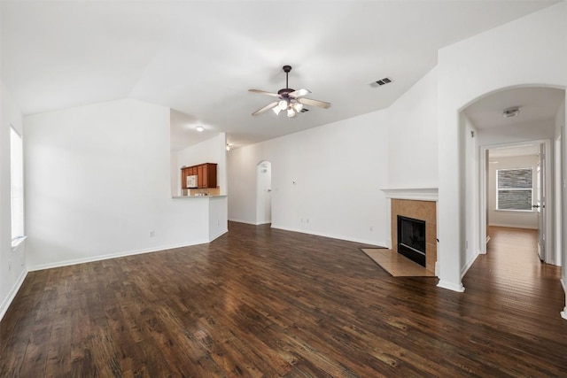 18513 Silent Water Way, Pflugerville, TX 78660 - unfurnished living room featuring vaulted ceiling, arched walkways, ceiling fan, dark wood-style flooring, and a tiled fireplace