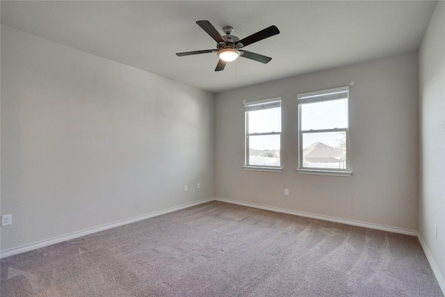 carpeted spare room featuring ceiling fan and baseboards