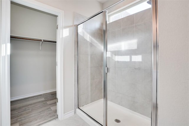 bathroom with baseboards, a walk in closet, and a stall shower