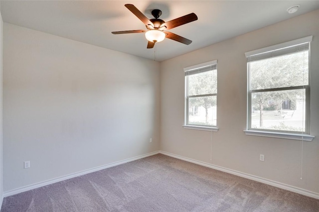 carpeted empty room with a ceiling fan and baseboards