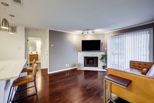 living area featuring visible vents, baseboards, a tiled fireplace, dark wood finished floors, and crown molding