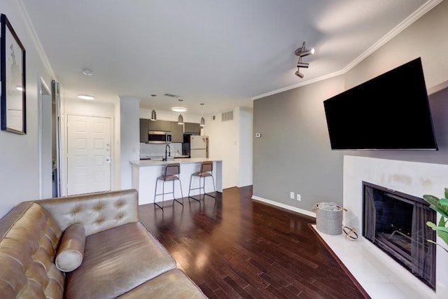 living room featuring visible vents, baseboards, crown molding, wood finished floors, and a fireplace with flush hearth
