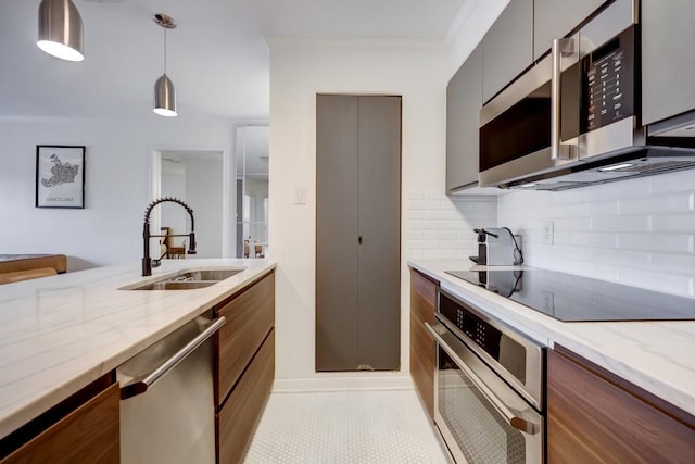 kitchen with stainless steel appliances, light stone countertops, a sink, and backsplash