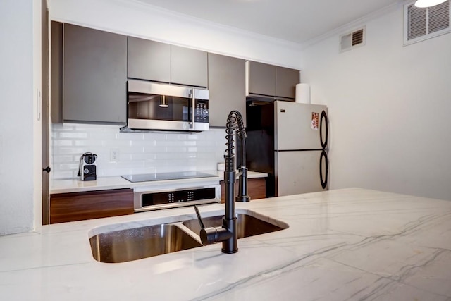 kitchen with visible vents, ornamental molding, freestanding refrigerator, stainless steel microwave, and gray cabinets