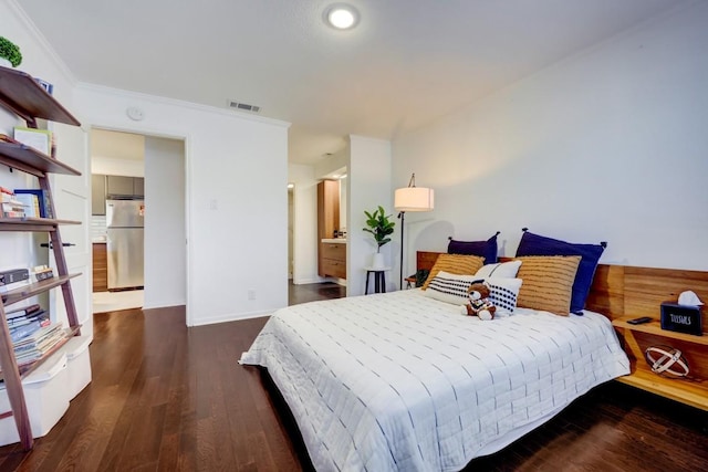 bedroom featuring ornamental molding, visible vents, freestanding refrigerator, and wood finished floors