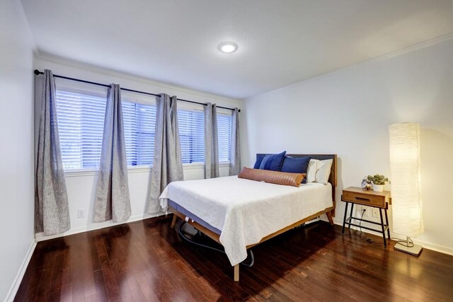 bedroom with baseboards, ornamental molding, and wood finished floors