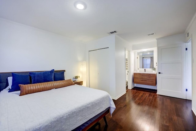 bedroom with dark wood-type flooring, ensuite bathroom, baseboards, and visible vents