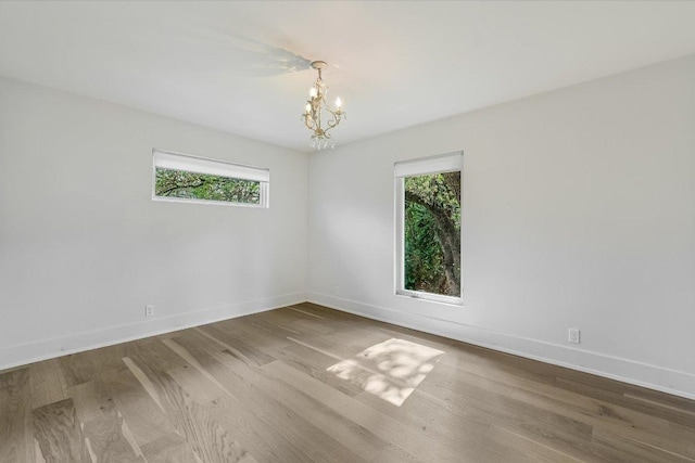 201 Westwood Ter, West Lake Hills, TX 78746 - spare room featuring baseboards, a healthy amount of sunlight, an inviting chandelier, and wood finished floors