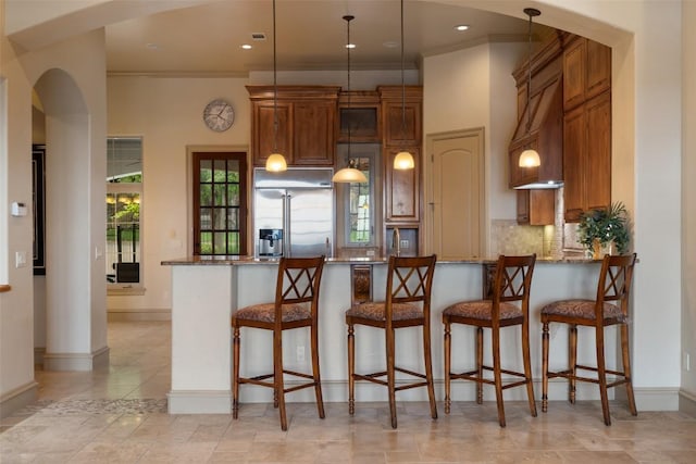 11913 Preserve Vista Ter, Austin, TX 78738 - kitchen featuring built in refrigerator, arched walkways, stone counters, backsplash, and a peninsula