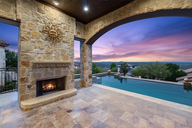 11913 Preserve Vista Ter, Austin, TX 78738 - pool at dusk with an outdoor stone fireplace, a patio area, and an outdoor pool